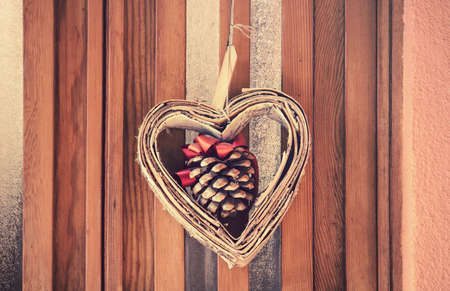 heart with colors of fall, in the middle of the symbol of love there is a pinecone with a red bowの写真素材