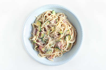 spaghetti with ham and zucchini with cheese, top view of the plate on white backgroundの写真素材
