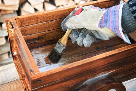 Varnishing a wooden object. Closeup of brush, the hand of worker wears a protection gloveの写真素材