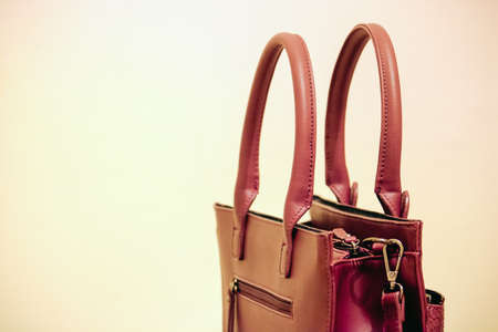 brown women purse on yellow background, the bag is closed - image with copy spaceの写真素材