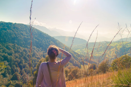 Woman looking far away, gesture with hand over head in a beautiful natural environment (light lens...