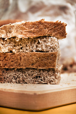 detail of brown bread, closeup of Sliced whole wheat food on a wooden chopping board (vertical...