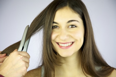 Girl gets her hair ironed smilingの写真素材