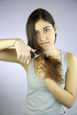 Girl cuts all her long hair with scissors unhappy of itの写真素材