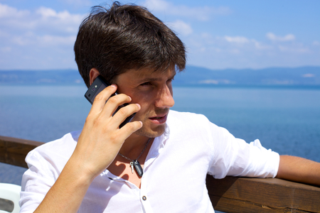 Serious man talking on the phone in front of lake in Italyの写真素材