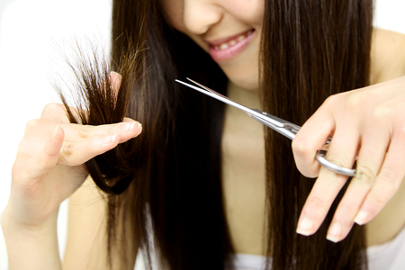 Scissors cutting ruined long black hairの写真素材