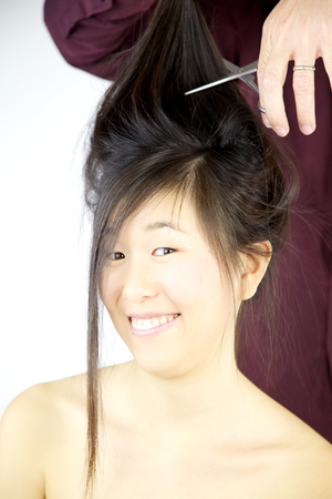 Happy asian woman getting all hair cut by hairdresserの写真素材