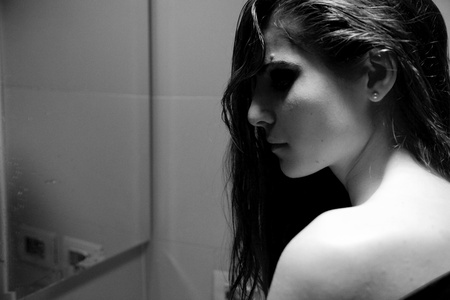 Young woman feeling desperate and alone in front of mirrorの写真素材