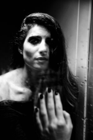 Young woman feeling desperate and alone in front of mirrorの写真素材