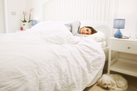 Cute maltese puppy dog sleeping close to womanの写真素材