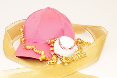 Girl's pink cap, baseball, and the glisten of gold ribbons reflect the gift of sports for girlsの写真素材