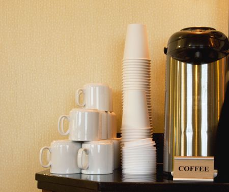 Coffee station equipped with ceramic mugs and paper cups for quick, caffeinated refreshmentの写真素材