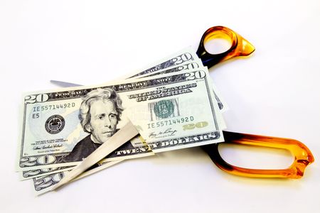 American dollars cut by bright orange scissors on white background reflect consumer's loss of spending powerの写真素材
