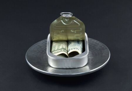 Dollar and yen currency are rolled together into an open sardine can in a reflection of a new, basic diversification of investments の写真素材