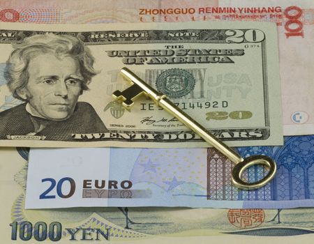 Golden key placed on multiple currencies,Dollars,  Euro, Yen, and RMB for worldwide business representation and empowermentの写真素材