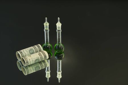 Two laboratory beakers with currency on mirror with light flare on green beakers to enhance success potential of investment in science;の写真素材