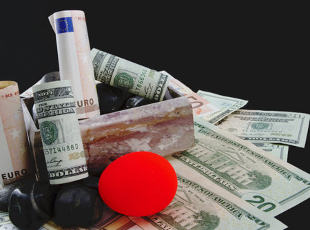 Marble box with euro and dollar currency and a reddened nest egg on the rocks depict troubled European and American pensionsの写真素材
