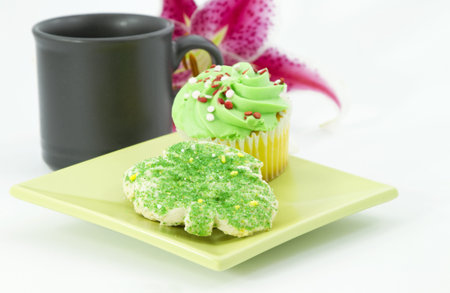 A morning break is shown with coffee, cupcake, and sugar cookie.  Single lily blossom in background adds suggestion of spring, summer, and casual elegance. の写真素材