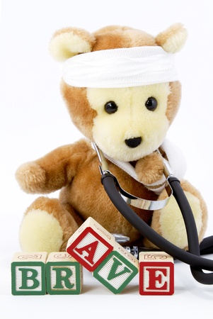 A stuffed bear wears a real stethoscope around its neck, has his arm in a sling, and has gauze wrapped around his head to display a special courage.の写真素材