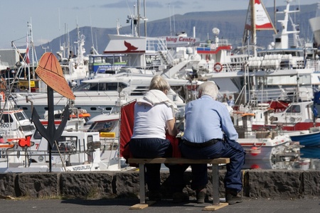 Reykjavik, Iceland - July 13, 2009:  Mature man and woman sit on bench at Reykjavik's Old Harbor area.  The old harbor was originally built 1913-17.  It is popular spot in Iceland's capital city for locals and tourists to stroll.のeditorial素材