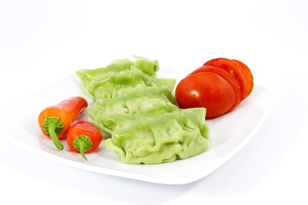 Vegetable gyoza, fresh red peppers, and sliced tomatoes on a white plate make for a vegetarian delight; gyoza is a Japanese dumpling.の写真素材
