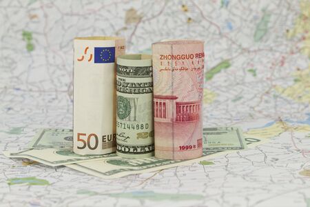 Euro, dollar, and yuan currencies placed together with map behind, indicative of the connected nature of global economyの写真素材