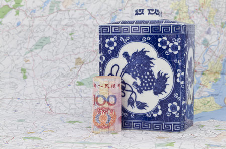 China's yuan currency placed on a map in front of an antique Chinese porcelain serves to symbolize...