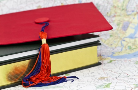 Graduation cap placed on book and maps allow symbols of transition and achievement o blend with an image of the journey and new paths.の写真素材