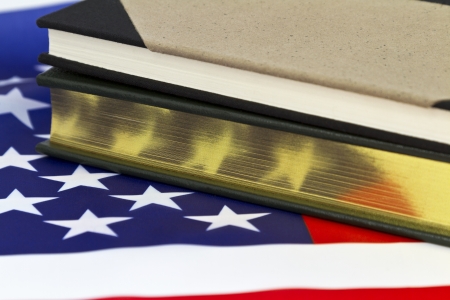 Book with gold edged pages and fabric journal placed on American flag depict success, leadership, government work, important information, or relevant history.  の写真素材
