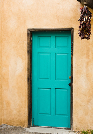 Old Pueblo Spanish style building with adobe walls enhanced by blue door with hanging red peppers.  Location is Old Town district in Albuquerque, New Mexico, in America's Southwest region.  Vertical image with copy space.の写真素材