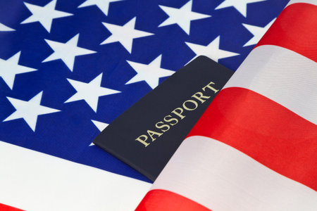 Stars and stripes of American flag are placed behind a passport reflecting pride in citizenship and...