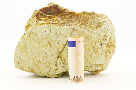 Large rock with crack line behind euro currency placed on white background depicts rough financial environment for European Union.の写真素材