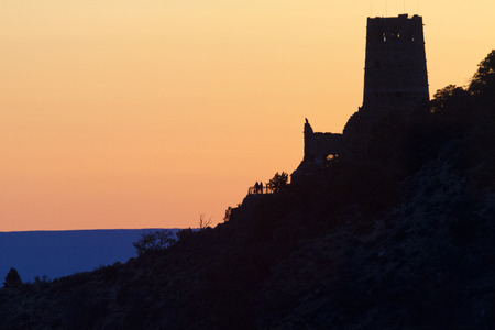 Sunrise colors the sky seen from Grand Cayon's Navajo Point along the South Rim's Desert View Scenic Drive.  Distant silhouette of couple at the Watchtower adds to scene's serenity.の写真素材