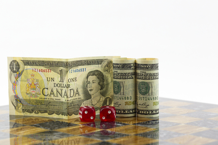 Red dice, game board, Canadian dollar, and American dollar reflect risk and opportunities in economic diplomacy.の写真素材