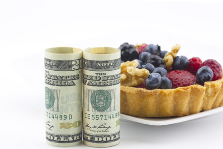 Lifestyle investments in healthy living industries reflected in money placed with healthy, colorful berries and nuts in tasty, fresh tart crustの写真素材