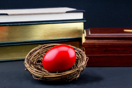 Books and wood box with red nest egg in front reflect fear and loss in even smart investments 