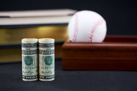 Successful strategic sports investments, professional or academic, reflected in baseball, books, box, and American dollars currencyの写真素材