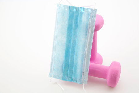 Coronavirus mask and light weights reflect message of both staying safe and staying fit during pandemic crisisの写真素材