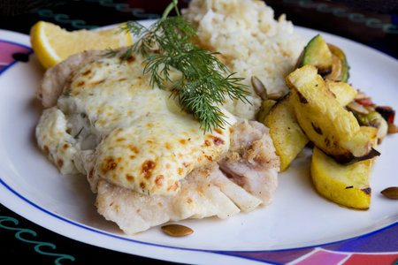 Cod fish with roasted vegetables and rice pilaf dressed with cheese saude, dill sprig, and lemon...