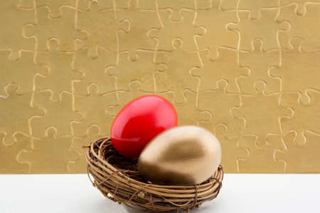 Gold puzzle background with golden and red nest eggs is financial and economic conceptual image emphasizing challenge and strategyの写真素材