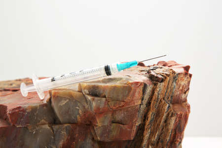 Injection needle on rock reflects solid public health recommendations with firm data to support vaccine guidance in conceptual imageの写真素材