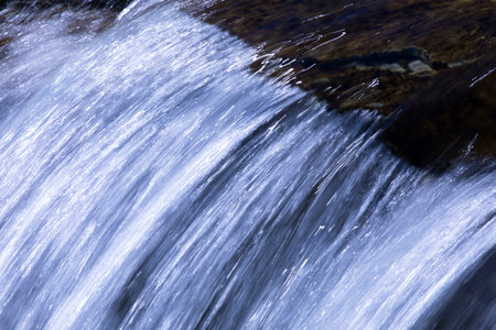 Minimalist nature close up of falling water along Creek on Going to the Sun Road in Glacier National Park in Montana. Copy space in light or dark flow.の写真素材