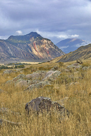 Picturesque vertical landscape with foreground rock accent to mountains and fields of Yellowstone Trail in Gardiner, Montanaの写真素材