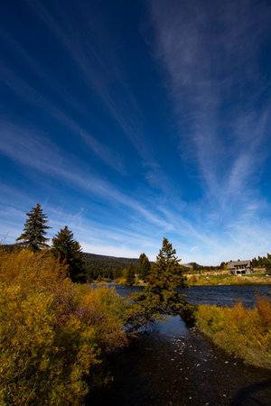 Clouds streak upward in blue sky above Madison River Recreation Area, a famed fly fishing region in Montana, United Statesの写真素材