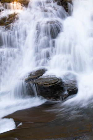 Beautiful cascading waterfall, rock steps, and pure pool of falls along Going to the Sun Road in...