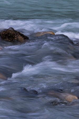 Natural background of silky textures of river currents over dark river rocks in Kootenay National Park in the Canadian Rockiesの写真素材