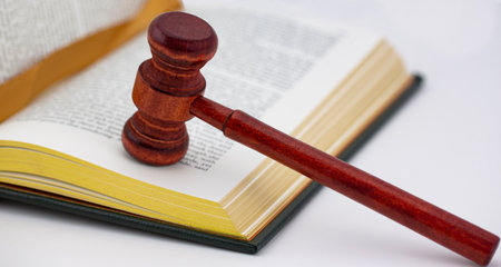Book with gilt page edges and worn ribbon bookmark placed with polished wood gavel on white background shows justice and educated law in unionの写真素材