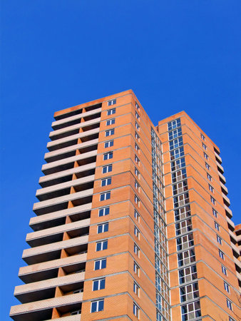 modern red brick building with many glass windows on blue sky. new construction concept