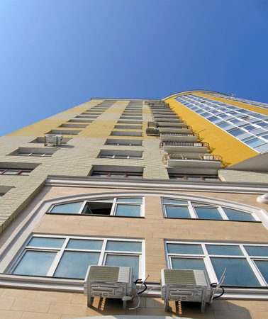 modern yellow building with many glass windows on blue sky, new construction concept