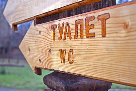focus on wc. restroom (toilet) as text on russian, wooden direction signの写真素材
